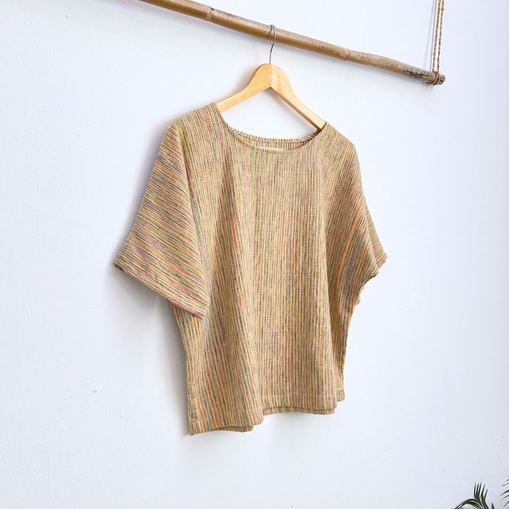 Striped multicolor top on a hanger against a white wall