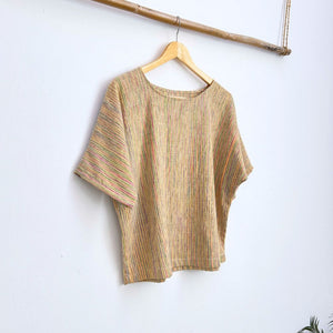 Striped multicolor top on a hanger against a white wall