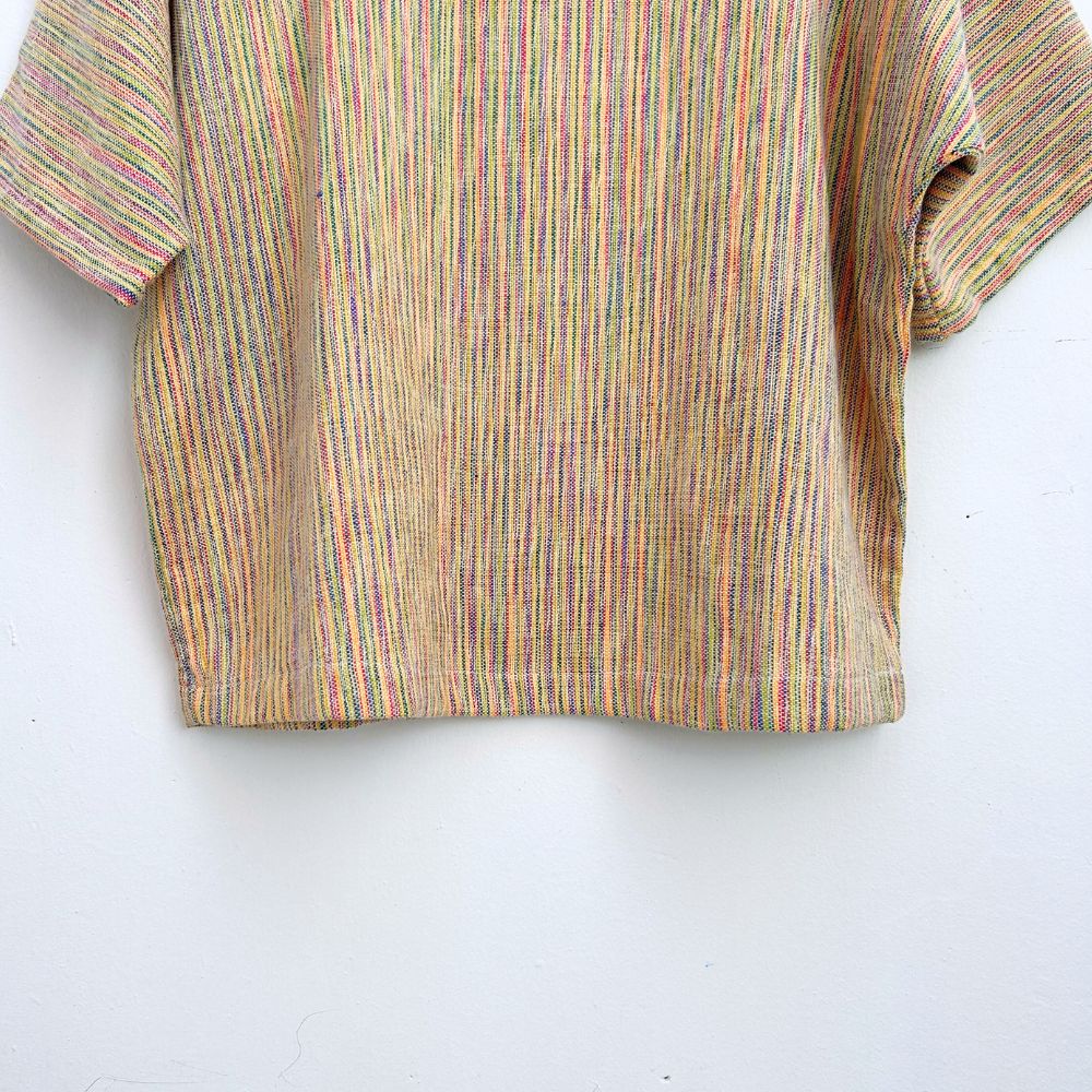 Striped multicolor top on a hanger against a white wall