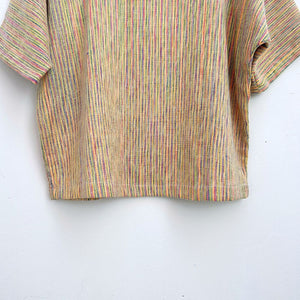 Striped multicolor top on a hanger against a white wall