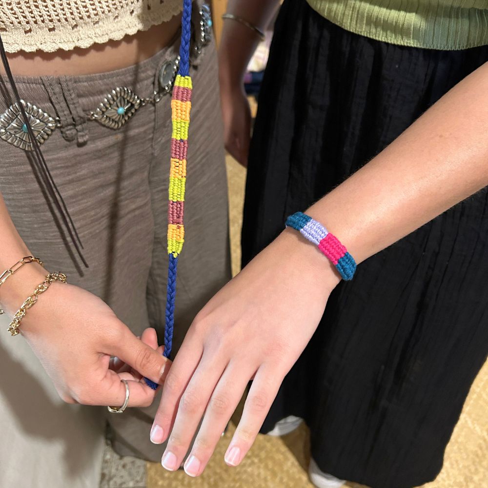 Two students proudly showing the finished bracelets they made by hand.