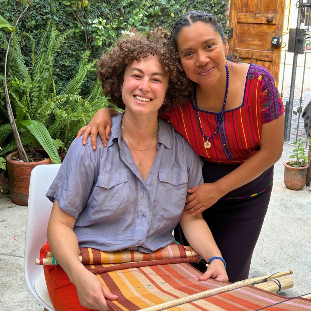 A student and her weaving teacher happily posing for a commemorative photo with their backstrap loom.