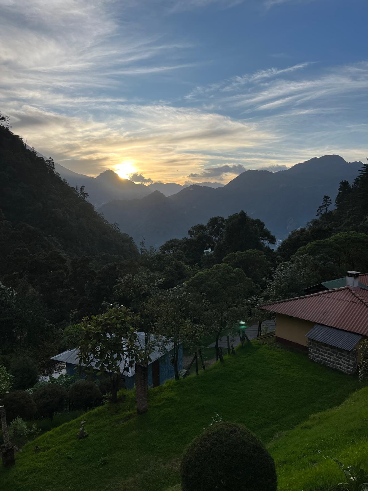 Sunset over mountains with houses and trees in the foreground