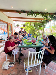 People sitting at a table with bright lighting outside, stitching together