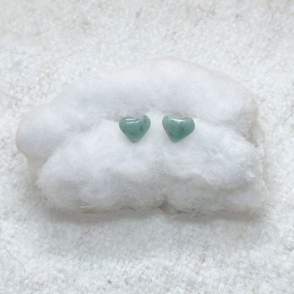 Heart-Shaped Light Green Jade Stud Earrings on a white cotton surface