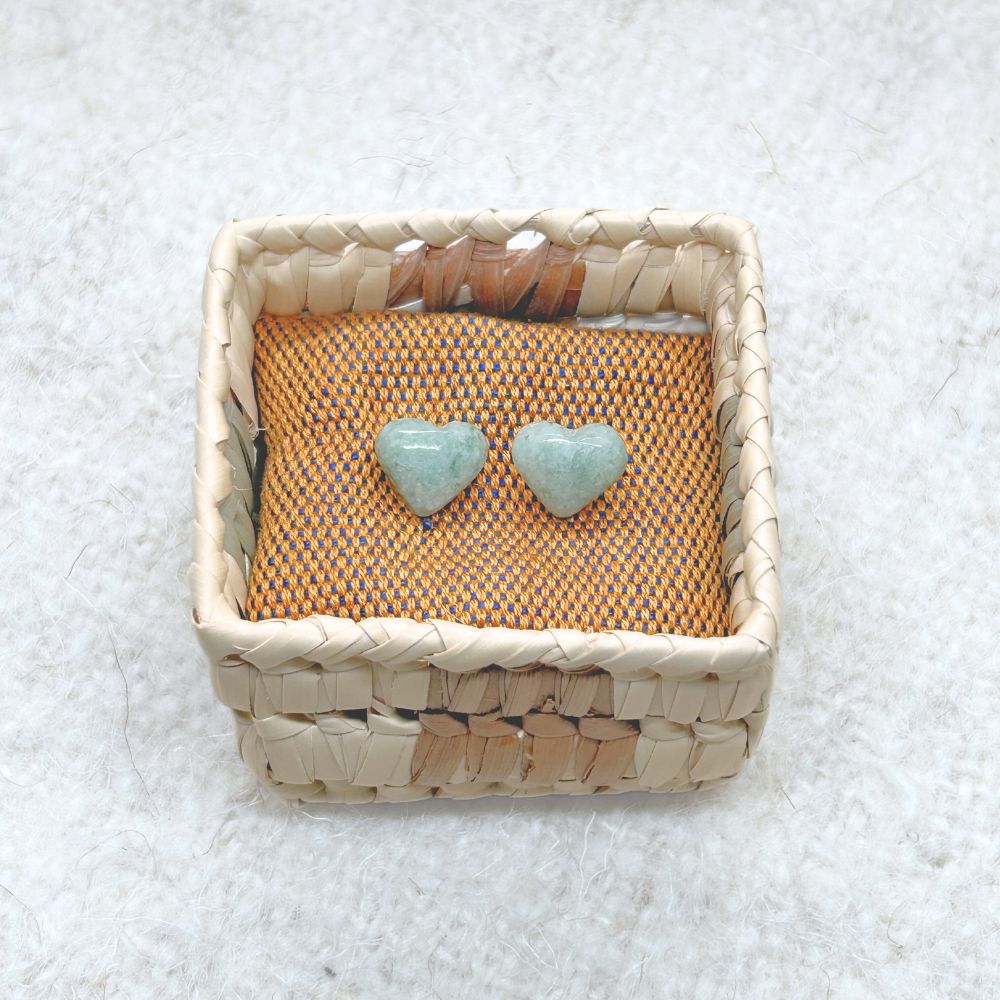 Heart-Shaped Light Green Jade Stud Earrings in a woven basket on a textured surface