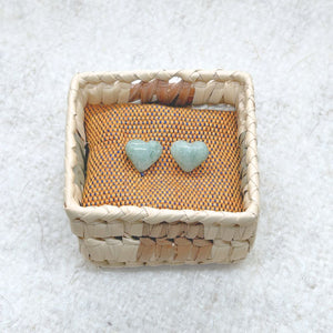 Heart-Shaped Light Green Jade Stud Earrings in a woven basket on a textured surface
