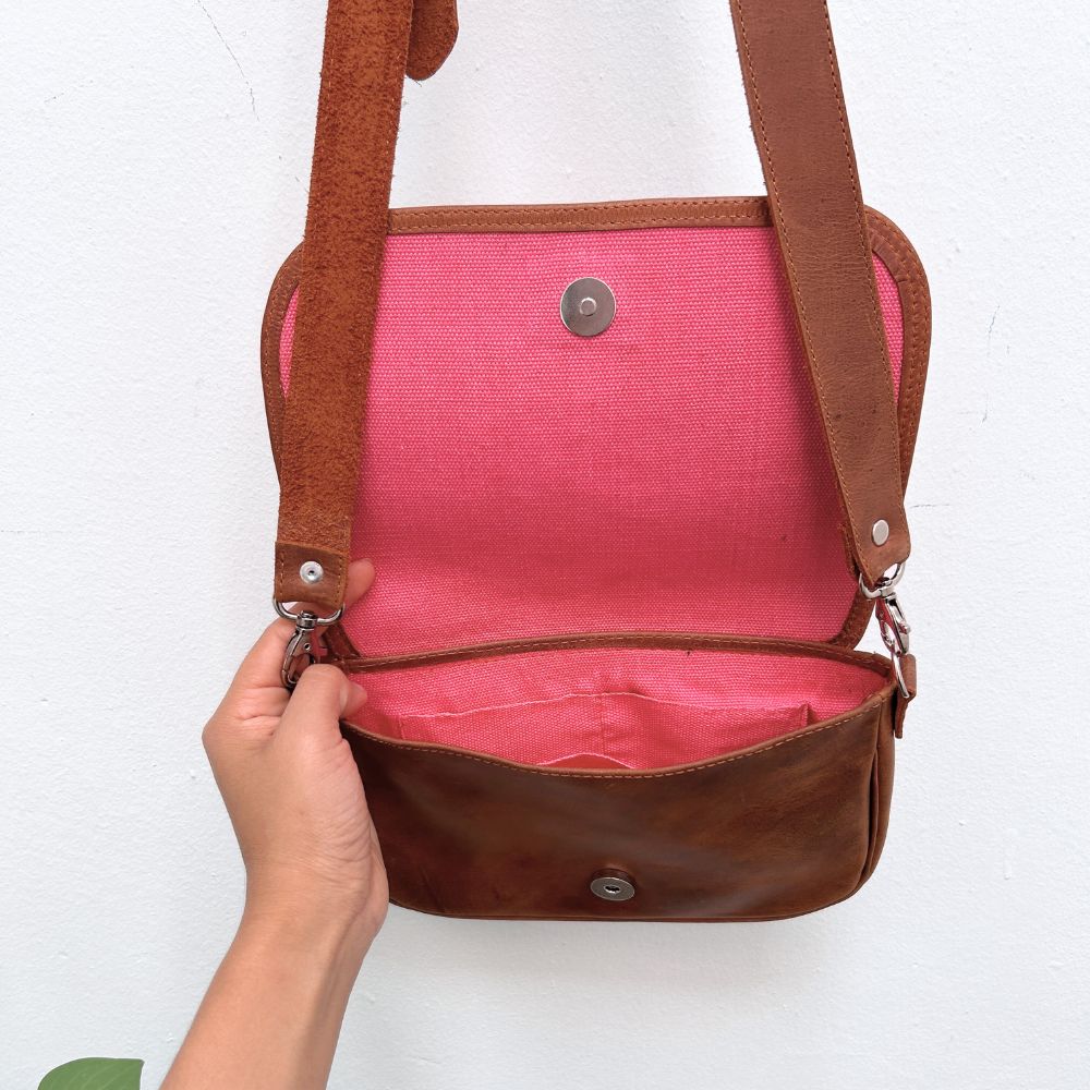 Brown leather handbag with pink interior on a white background
