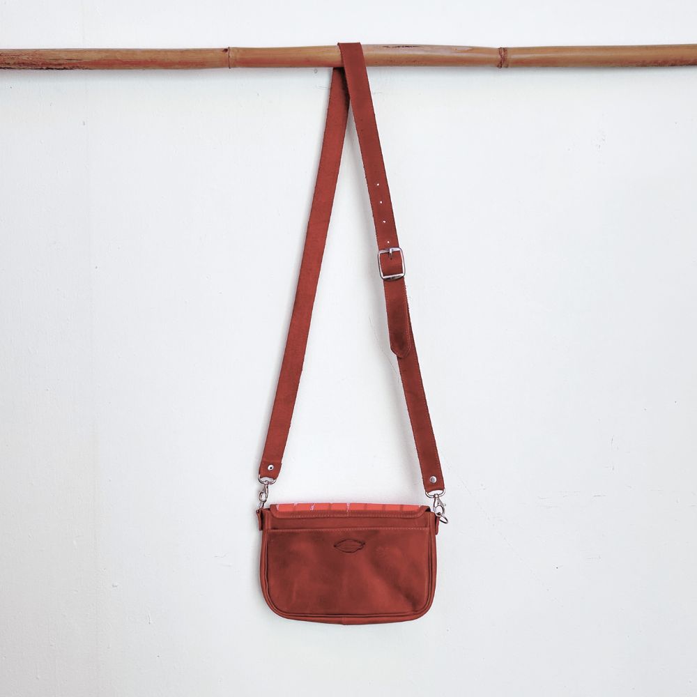 Brown leather crossbody bag with a strap on a white background