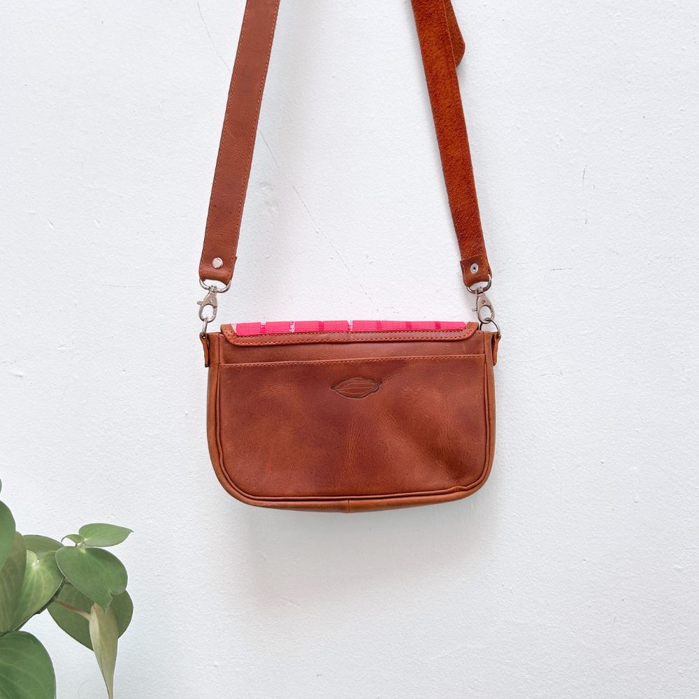 Brown leather crossbody bag with a pink interior on a white background