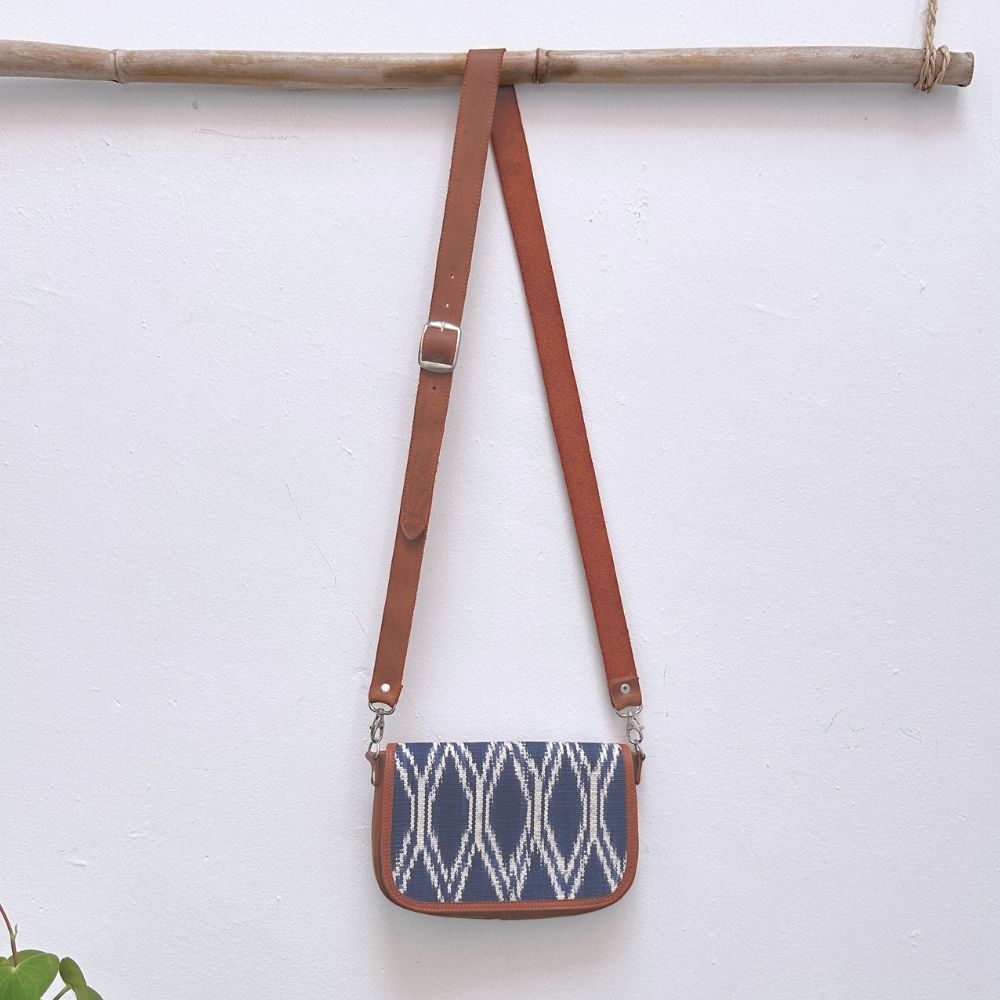 Blue patterned crossbody bag with brown strap on a white background