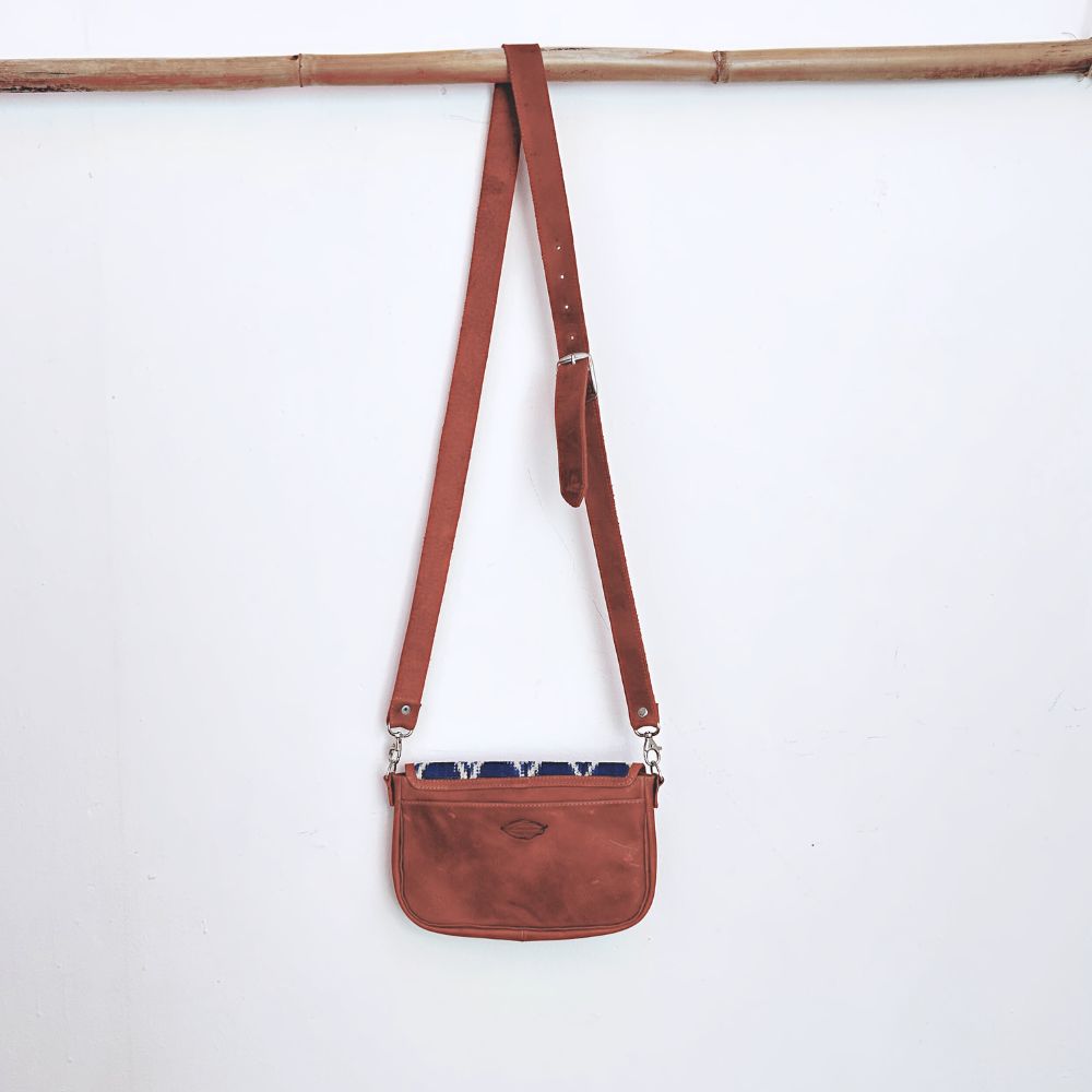 Brown leather crossbody bag with a strap on a white background
