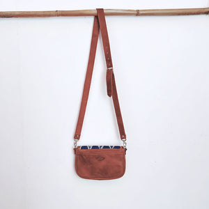 Brown leather crossbody bag with a strap on a white background