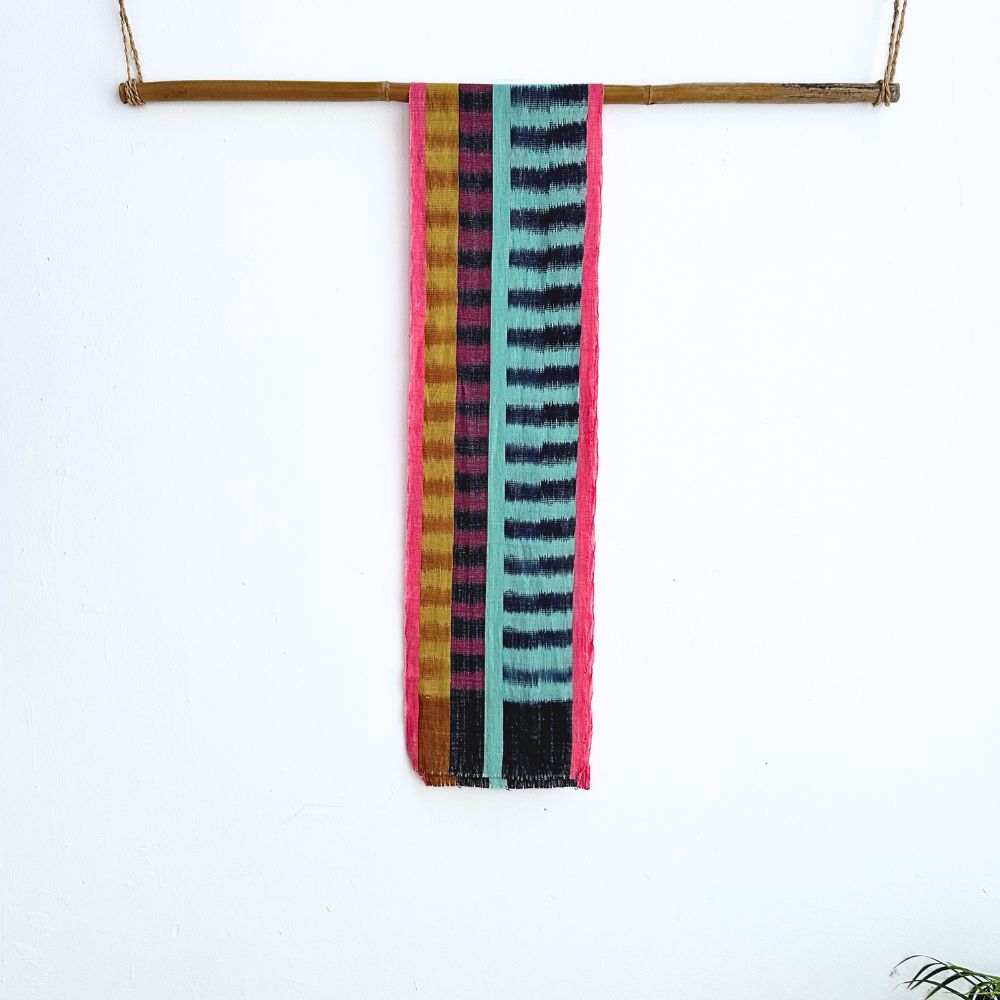 Colorful striped scarf hanging on a wooden rod against a white background