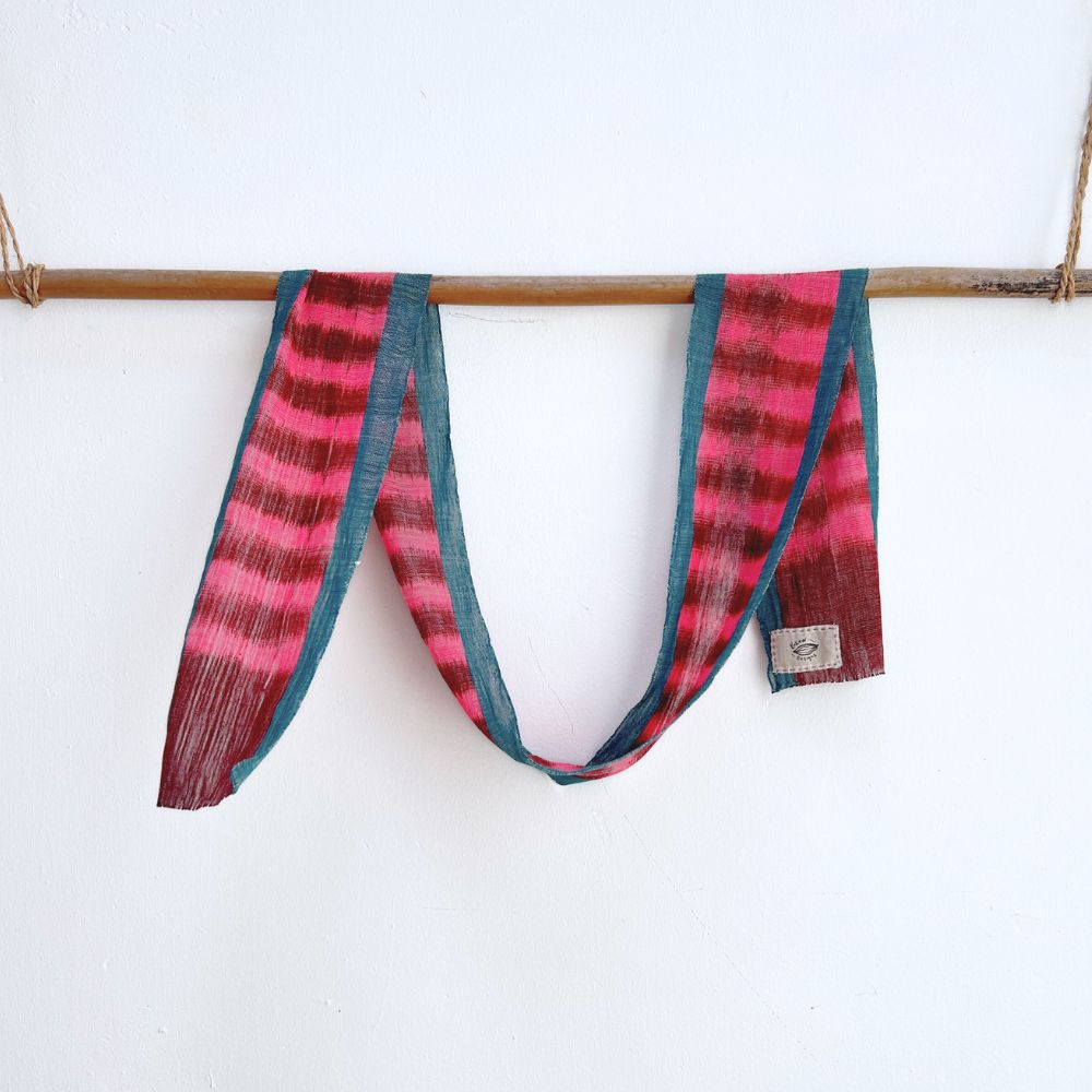 Naturally-dyed vibrant handwoven cotton scarf hangs on a bamboo rod