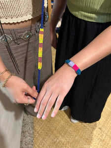 Two people wearing colorful bracelets on a textured surface