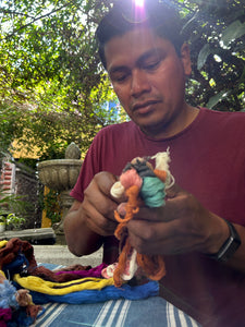 Our instructor Chato holding naturally dyed yarn before cutting it to create the pompoms.