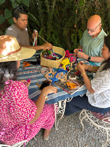 A group of people in the garden making their own Chajul pompoms with their instructor. All the colorful yarn is made from natural cotton and naturally dyed. Surrounded by nature.