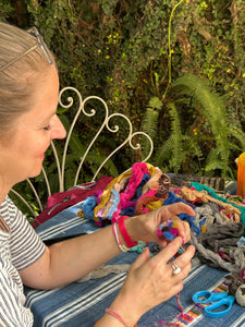 Close up of a student smiling while watching the pom pom creation process using the colors she selected herself.