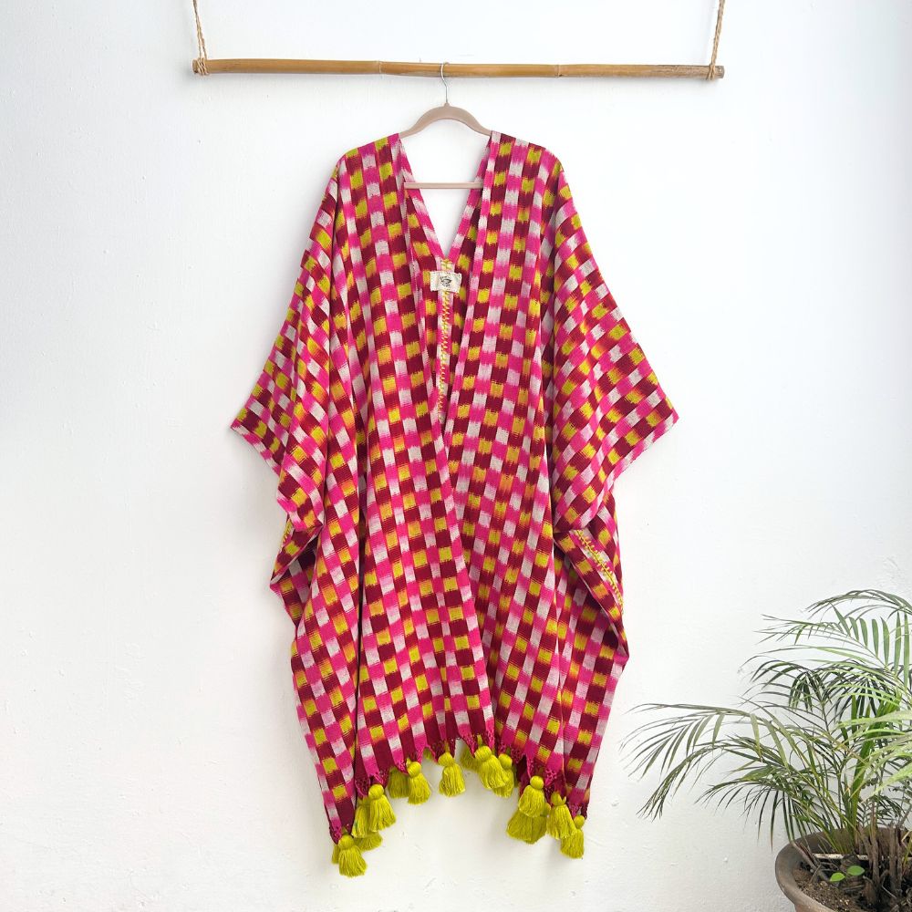 Colorful checkered garment with tassels on a hanger against a white background