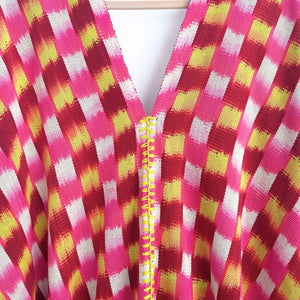 Close-up of a colorful checkered fabric with a zigzag embroidery detail on a white background