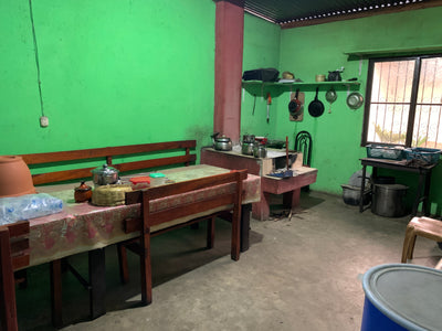 Kitchen with green walls, wooden tables, and various kitchen items.