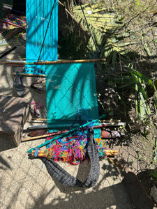 Colorful loom with turquoise fabric and yarn on a natural outdoor setting