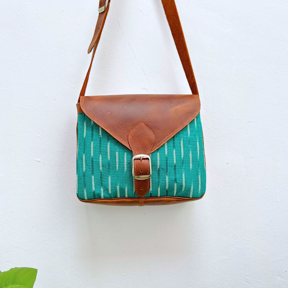 Green bag with brown leather accents on a white background