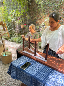 A woman in a traditional pikbil blouse warping on a wooden warping board.