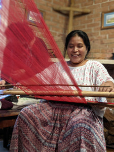 Master weaver demonstrating on a backstrap loom with a big smile.