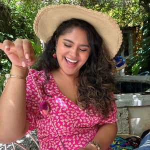 Our friend Mariaelena smiling happily while showing her finished pompom in pink tones.