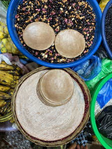 Baskets full of beans and other fresh produce at the market, with terra cotta comal plates 
