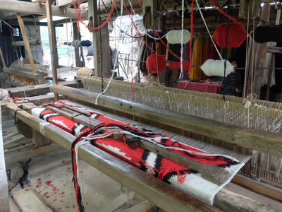 Weaving loom with red, black, and white wool yarns.