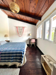 A well-lit bedroom with a bed, desk, and window