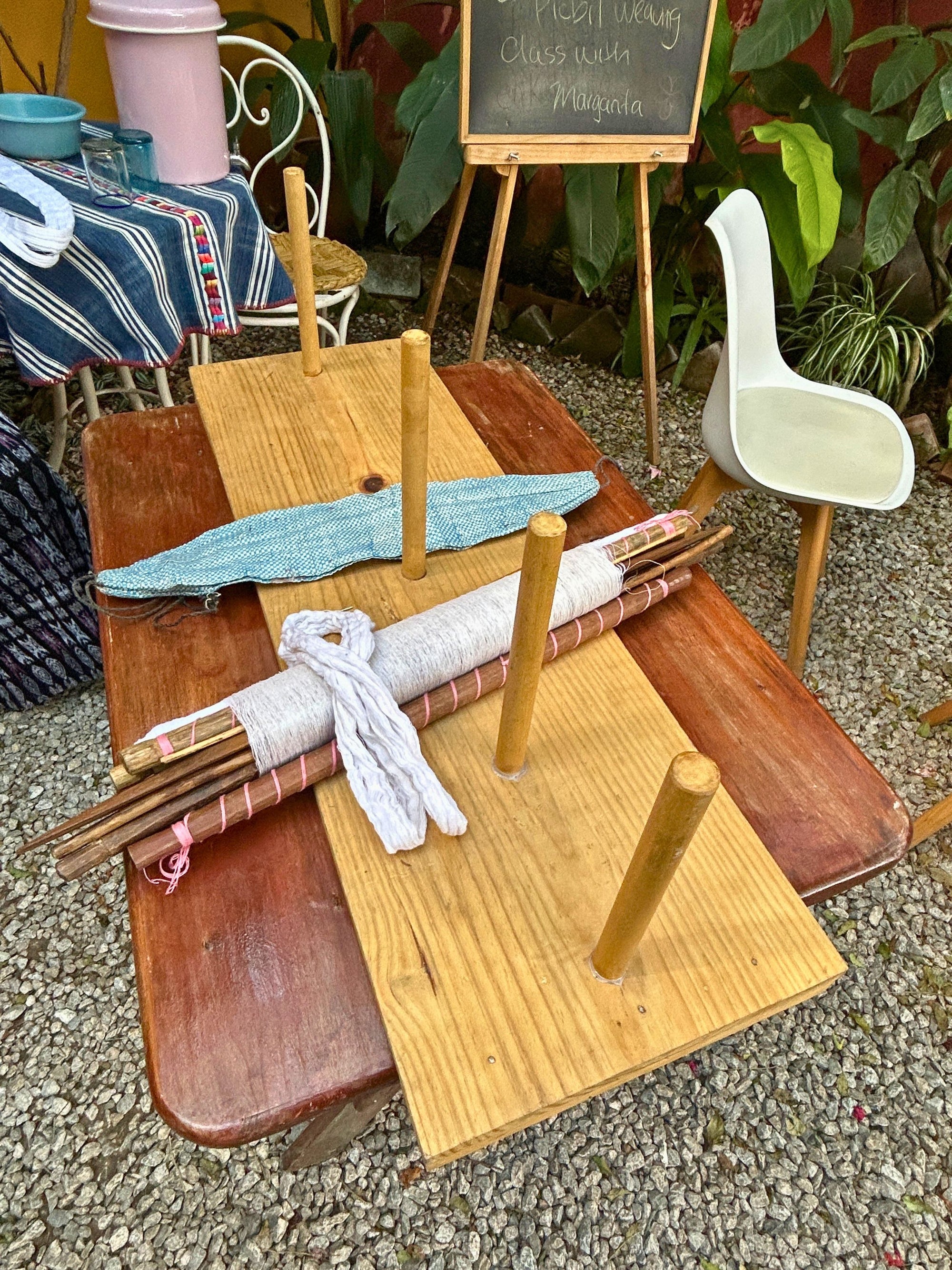 A weaving workstation displaying the warping board, backstrap loom, and traditional weaving materials used during the week.