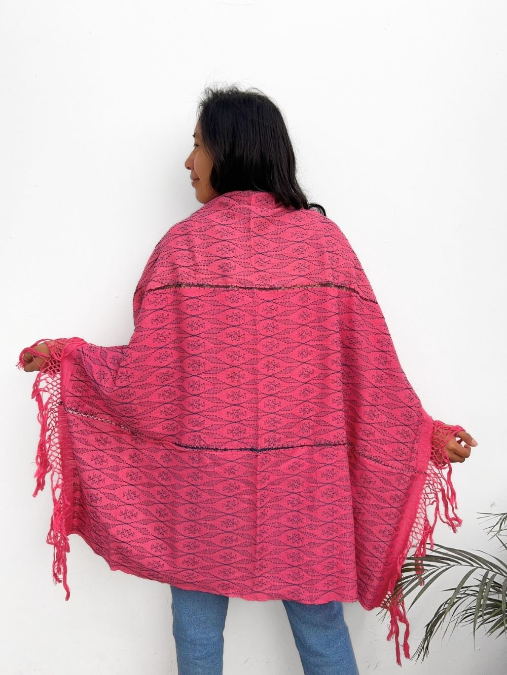 Person wearing a cochienal pink patterned shawl with fringes