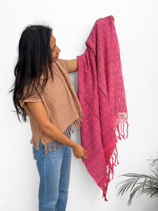 Woman holding a cochienal pink patterned shawl against a white background