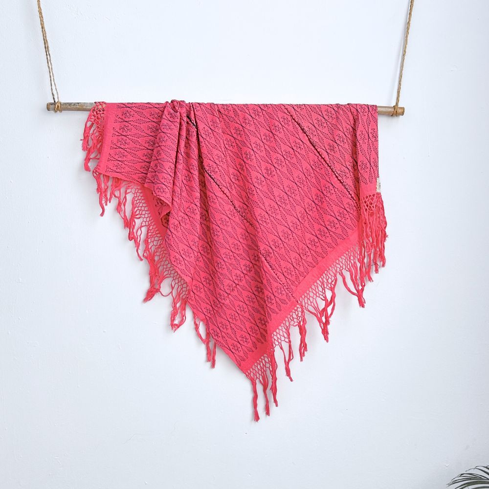 Pink shawl with fringes hanging on a white background