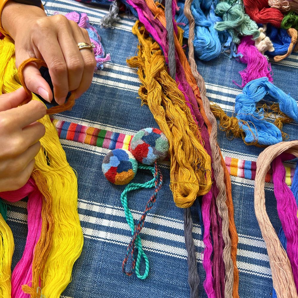 Close up of pompoms and naturally dyed threads used for creating the pompoms.