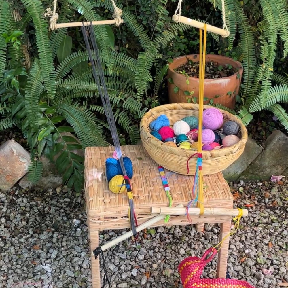 Basket with colorful yarn balls on a small wooden stool outdoors.