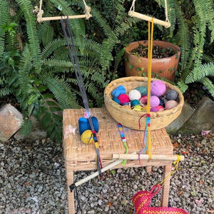 Basket with colorful yarn balls on a small wooden stool outdoors.