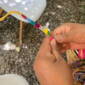 Close-up of hands tying a colorful bracelet 