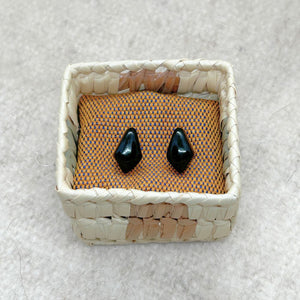 Rhombus-Shaped Black Jade Stud Earrings in a woven palm basket on a textured surface