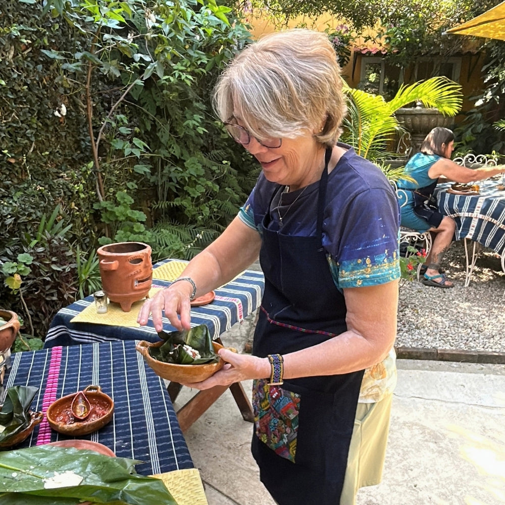 A participant serves herself tamales in a terra cotta traditional bowl.