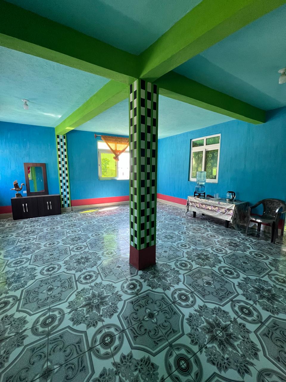 The living room is spacious, bright, and has a table with drinking water, a kettle for heating water, and an electric stove for guest use.