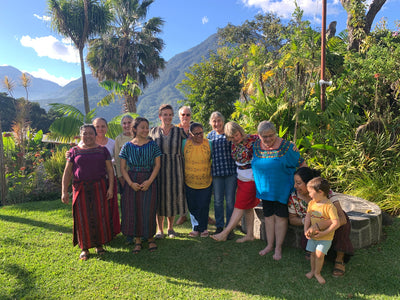 Group of people posing outdoors in a lush garden with volcanoes in the background