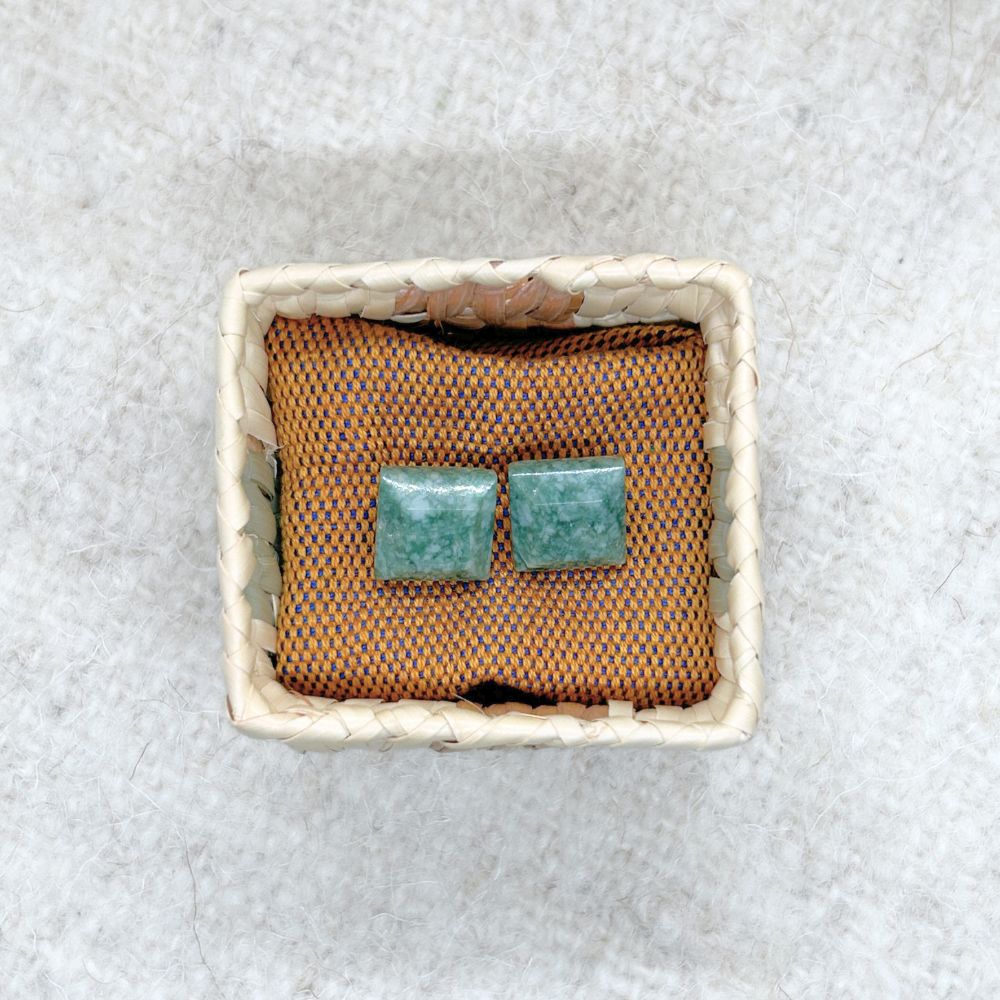 Pair of sSquare-Shaped Medium Green Jade Stud Earrings in a small woven basket on a textured surface