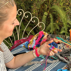 Close up of a student smiling while watching the pom pom creation process using the colors she selected herself.