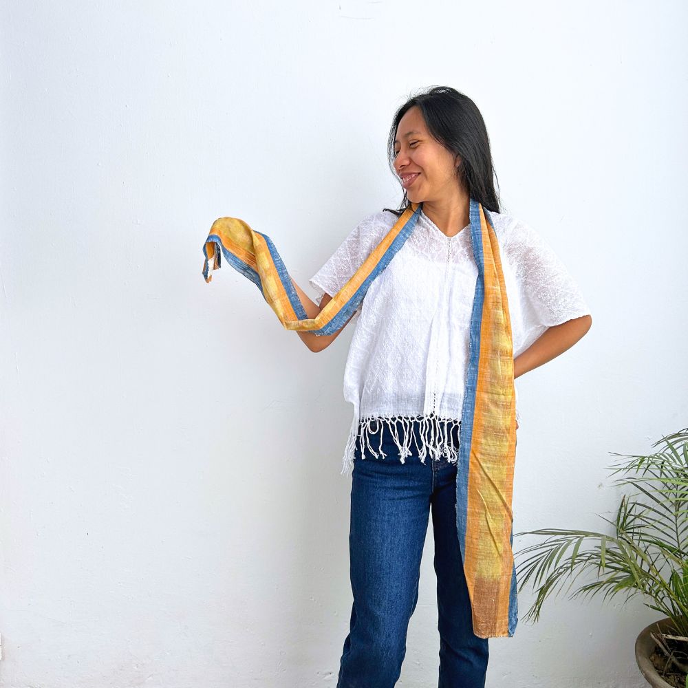Woman wearing a long, colorful scarf against a white background