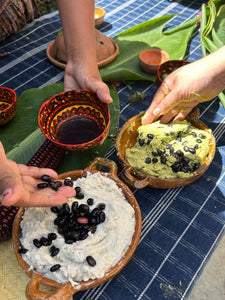Three bowls of different foods on a blue checkered tablecloth with hands interacting.
